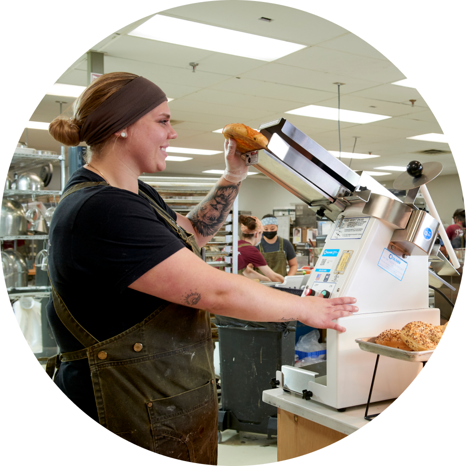 Bakery worker operating bread slicing equipment.
